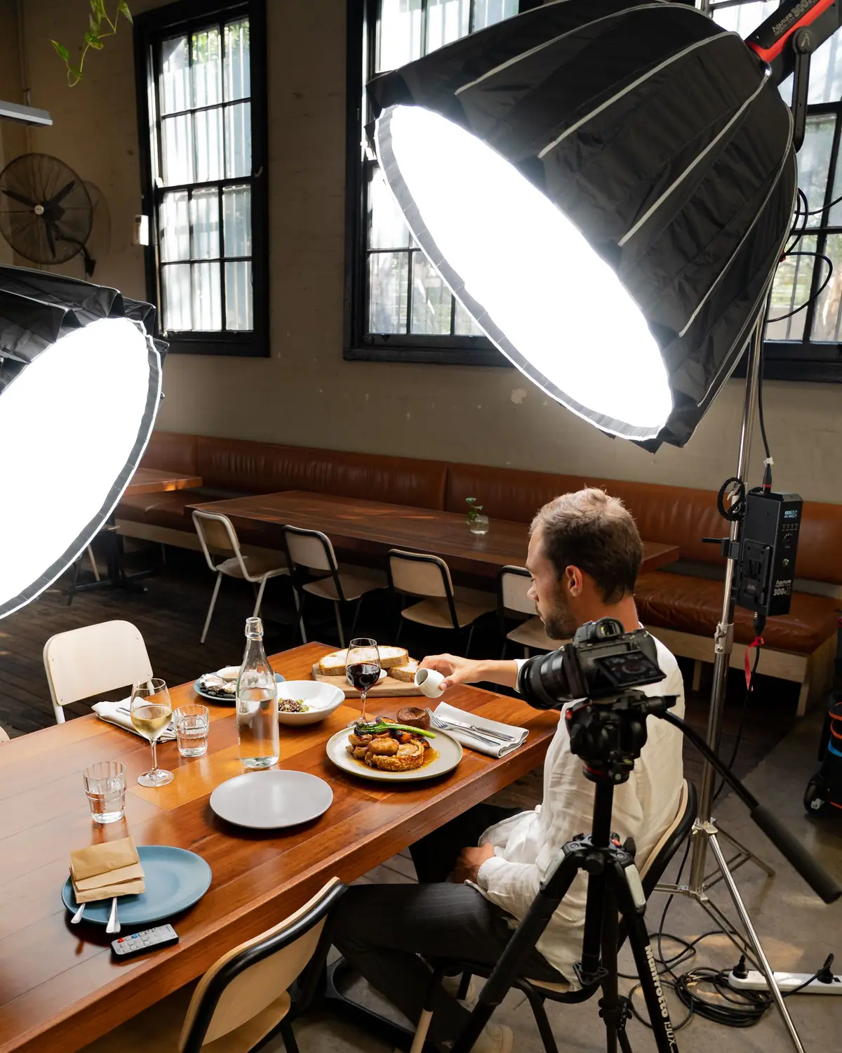 Fotógrafo produzindo um ensaio de comida dentro de um restaurante, com dois softboxes iluminando a mesa