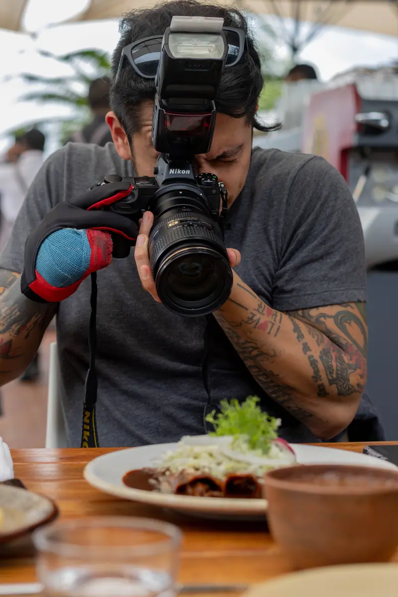 Fotógrafo com câmera profissional enquadrando um prato